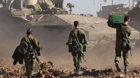 Israeli soldiers walking towards a tank