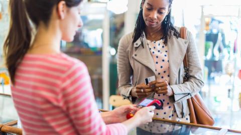 A woman getting ready to pay for goods in a shop using a debit or credit card