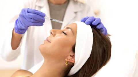 A stock image of a female patient receiving cosmetic treatment