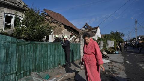 A woman wearing a pink dressing gown stands next to her house destroyed by a Russian air strike, amid Russia's attack on Ukraine, in Zaporizhzhia, Ukraine on 10 October 2024.