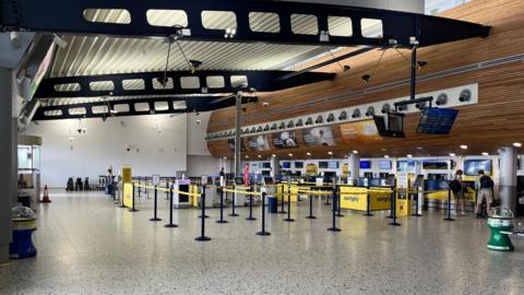 The picture shows Guernsey's airport terminal with check in desks with belt barriers for customers to queue behind.