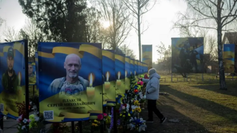 A woman pays her respects at portraits of fallen Ukrainian servicemen in Zavallia, central Ukraine. Photo: 10 February 2025