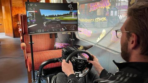 Gavin Field plays Grand Turismo video game in a simulator aboard a 1950s carriage at The Kent & East Sussex Railway in Tenterden