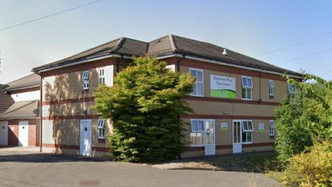 The two-storey building is made from red and sand-coloured brick with rows of white windows on both levels. A sign attached to the side of the building reads 'Haythorne Place Care Centre'.