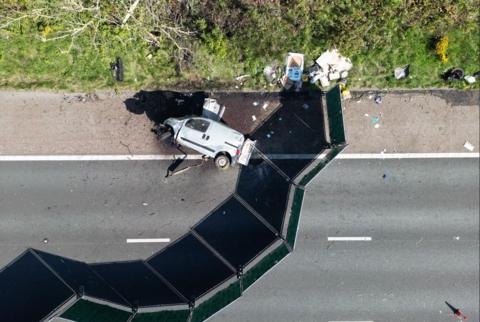 An aerial view of a damaged van on its side close to some debris on the motorway