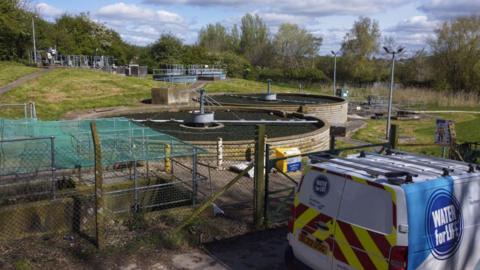 A van parked next to a water treatment works.