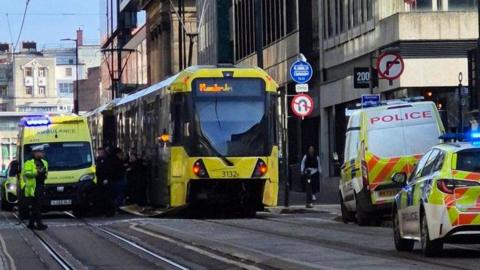 Tram flanked by ambulance and police vehicles at the collision scene