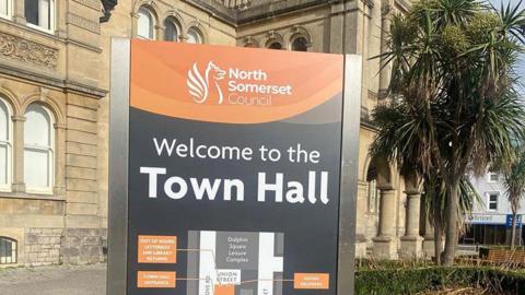 The exterior of Weston-super-Mare Town Hall, also home of North Somerset Council. The two-storey Victorian sandstone building has an engraved sign that says "town hall" and small garden either side of its entrance.