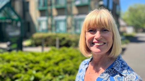 Jane Taylor wearing a blue and white dress outside Teignbridge District Council offices.