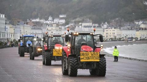 Farmers driving on Llandudno promenade with a sign on the front saying Labour War on Countryside 