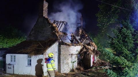 A building with a roof that is missing, with smoke emanating from the structure.