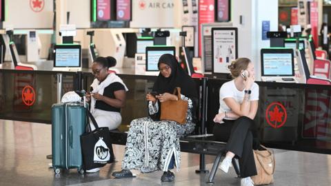Women sitting in an airport terminal on their phones