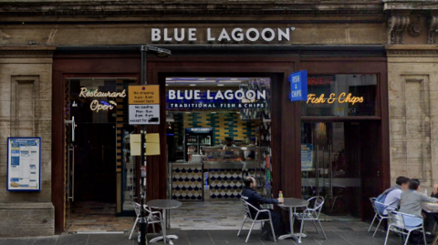 A google view of the front of the Blue Lagoon chi shop with four people sitting at tables on the street outside