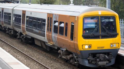 A West Midlands Railway train that is stationary at a platform. 