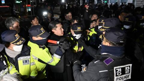 Police attempt to hold back people trying to enter the National Assembly in front of the main gate of the National Assembly in Seoul