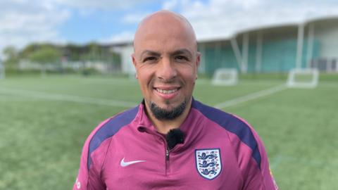 Fahd Saleh is wearing an England top with the "three lions" emblem
