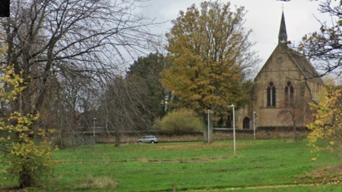 An open stretch of grassy land next to Christ Church in Felling on a cloudy day.