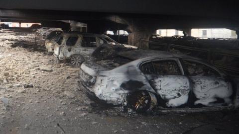 Burnt out cars in a stone car park