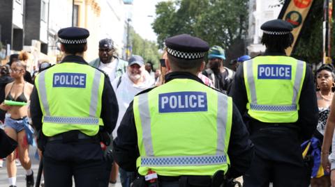 A general view of the back of three Metropolitan Police officers at Notting Hill Carnival. 