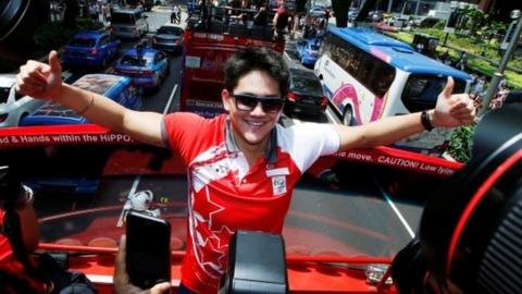 Singapore"s Olympic gold medallist swimmer Joseph Schooling poses for photos during a victory ceremony on an open top bus along Orchard Road in Singapore August 18, 2016.