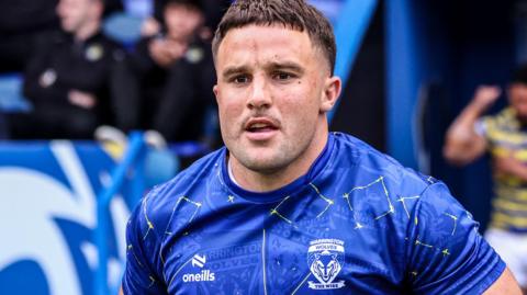 Josh Smith in blue Warrington shirt runs onto the pitch