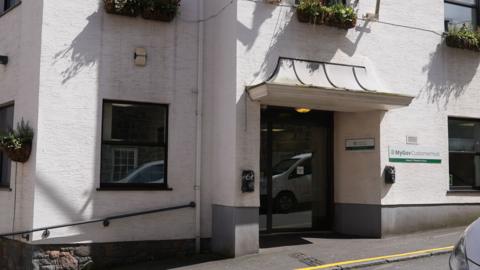 An entrance of a white office building with a MyGov Customer Hub sign.