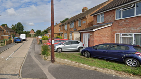 Terraces of brick houses and cars in Cinderford Close