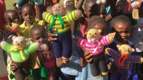 Children in Africa with knitted teddies
