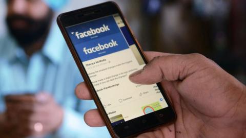 An Indian man looks at the Facebook app on his smartphone in Amritsar on March 22, 2018.