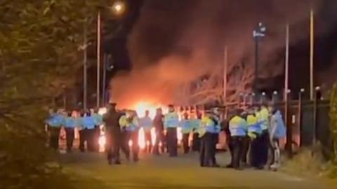 Police officers stood near a burning van