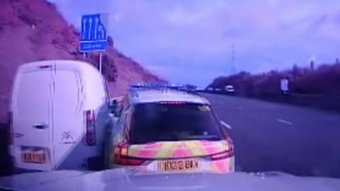 Police dashcam view of a polcie car crashed into a white van on the left hand lane of a motorway 