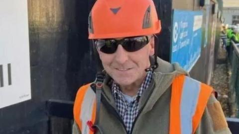 Glen Edwards wearing an orange hard hat, high-vis vest and sunglasses.