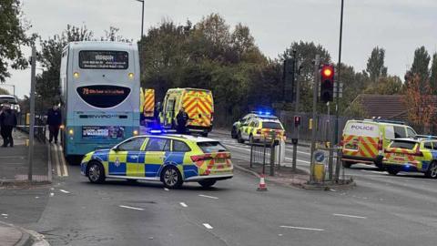 Several police vehicles have closed off Bobbers Mill Bridge, near Aspley Lane in Nottingham. A double-decker bus is situated on the left of the road.