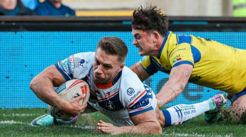 Wakefield Trinity full-back Matty Russell dives over the try line to score against Warrington Wolves