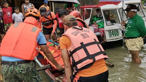 Rescue personnel assist a woman amidst flooding, after the tropical storm Megi hit, in Leyte Province