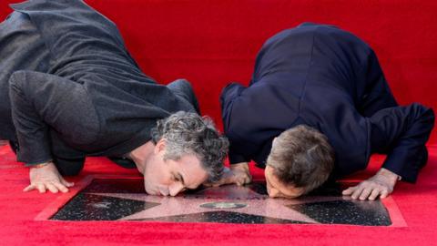 Actors Willem Dafoe and Mark Ruffalo kiss Dafoe's star on the Hollywood Walk of Fame