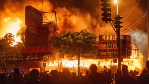 A liquor store burns near the Minneapolis police's third precinct