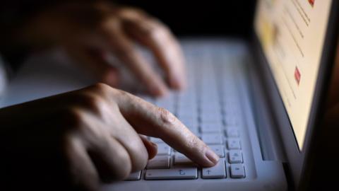 A person's hand on the keyboard of a laptop computer