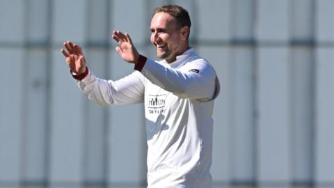 Liam Livingstone, wearing Lancashire cricket whites, celebrates with his hands held up to give a high-five and a smile on his face after taking a wicket against Kent
