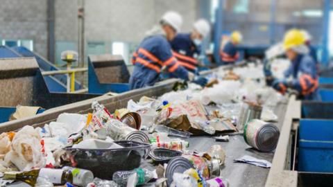 Workers at a recycling plant processing recycling materials such as cans and wrappers