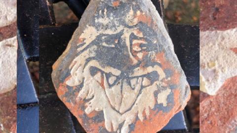 An ancient medieval tile depicting a lion's face