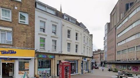 Terrace of buildings in Bournemouth with red phonebox at the front - most are flats on two storeys with shops below.