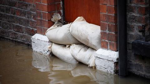 Sandbags in doorway of a house that is impacted by flooding