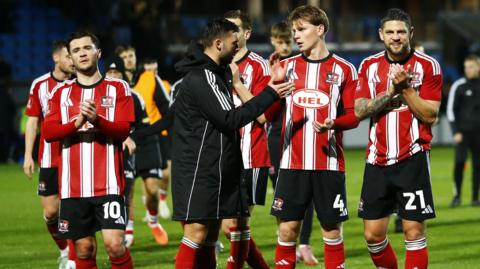 Exeter City players clap their fans