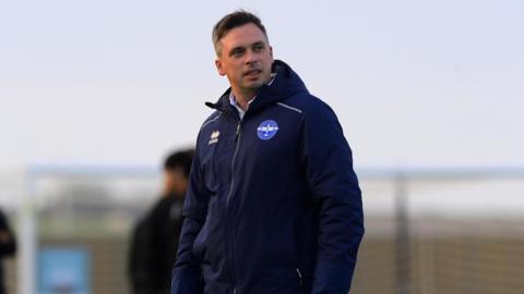Scott Bartlett stands on the touchline as manager of Eastleigh.
