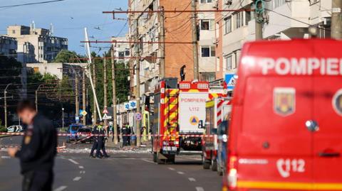 Emergency service workers and vehicles outside an apartment building hit by a drone, in the city of Galati, Romania