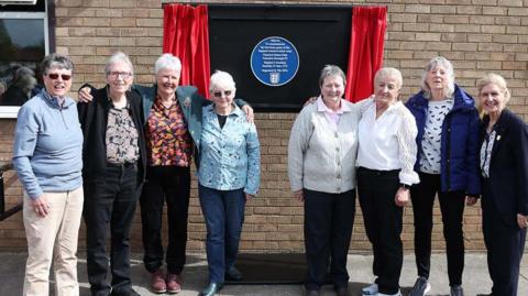 Members of the 1973 England squad who beat Scotland 8-0. The eight players are standing in front of a blue plaque which has been unveiled in Nuneaton. 
