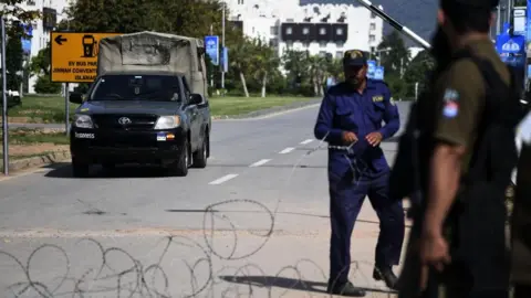 Pakistani security personnel standing at a roadside blockade.