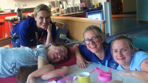 Three hospice support staff members are sitting next to a patient.