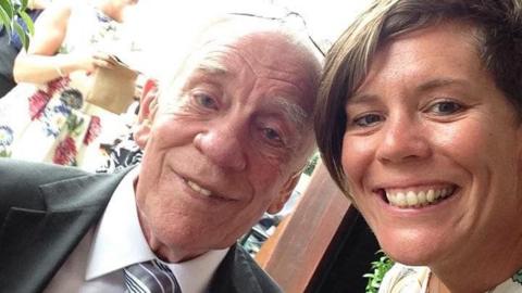 A lady with short brown hair and an older man smiling at the camera